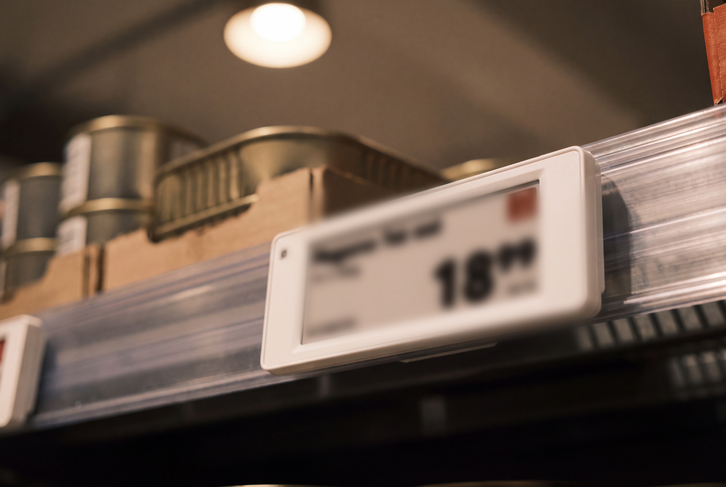 Macro close-up of an electronic shelf label on a shelf-edge rail.
